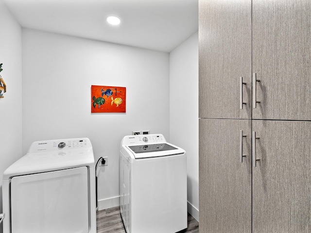 laundry room with wood finished floors, cabinet space, washing machine and clothes dryer, baseboards, and recessed lighting