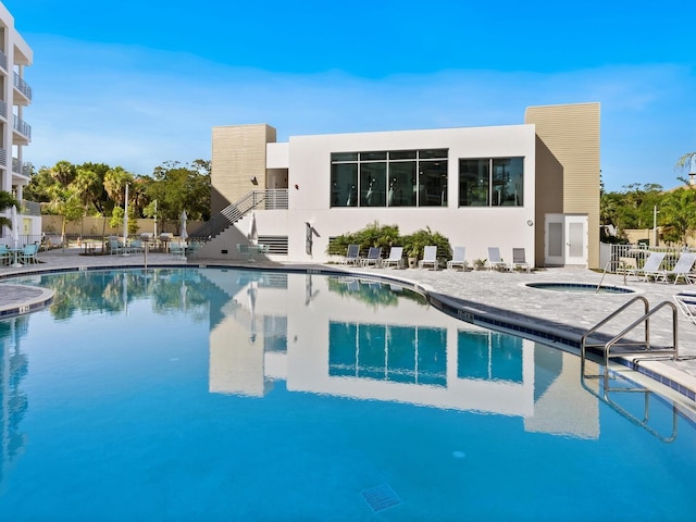 community pool with a hot tub, fence, stairs, and a patio area