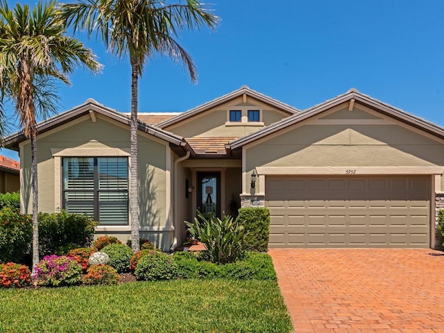 5952 Snowy Egret Dr, Sarasota, FL 34238 - view of front of home featuring an attached garage, a front lawn, decorative driveway, and stucco siding