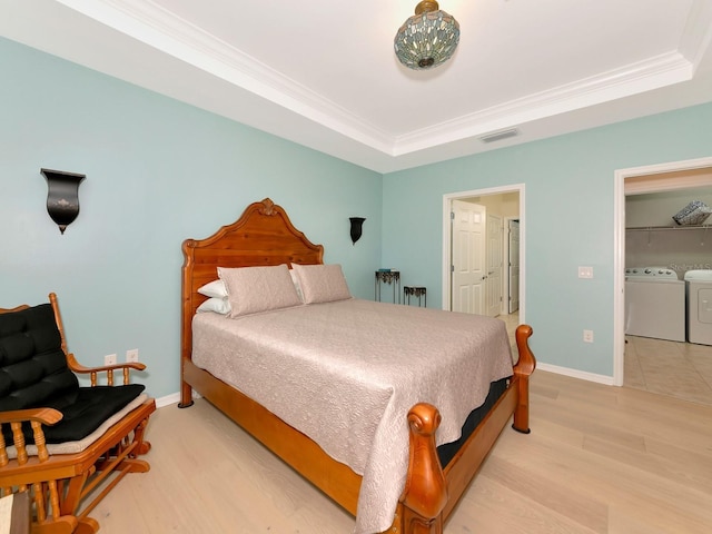5952 Snowy Egret Dr, Sarasota, FL 34238 - bedroom featuring ornamental molding, light wood-style flooring, visible vents, a tray ceiling, and washing machine and clothes dryer