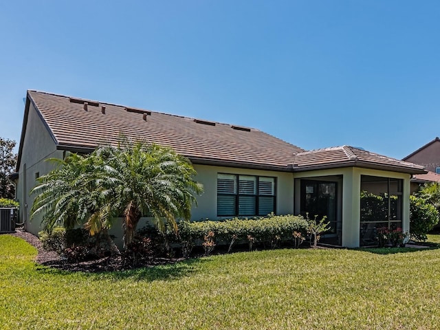 5952 Snowy Egret Dr, Sarasota, FL 34238 - back of house featuring central AC unit, a sunroom, a tiled roof, a yard, and stucco siding