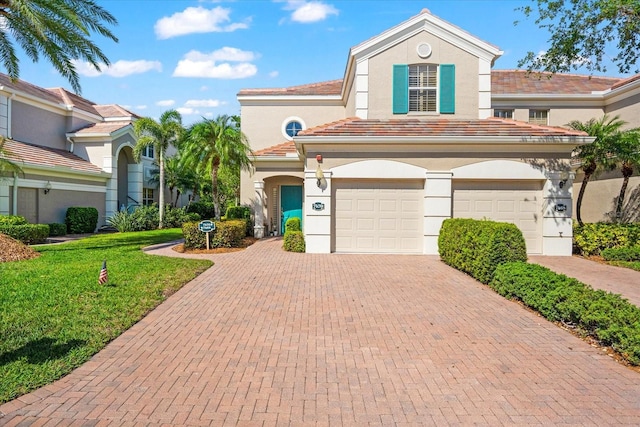 mediterranean / spanish-style home featuring a garage, a front yard, stucco siding, and decorative driveway