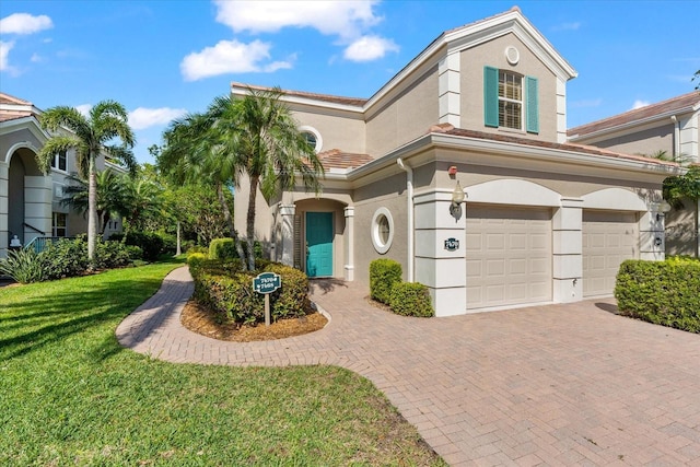 mediterranean / spanish home featuring a front lawn, a garage, decorative driveway, and stucco siding