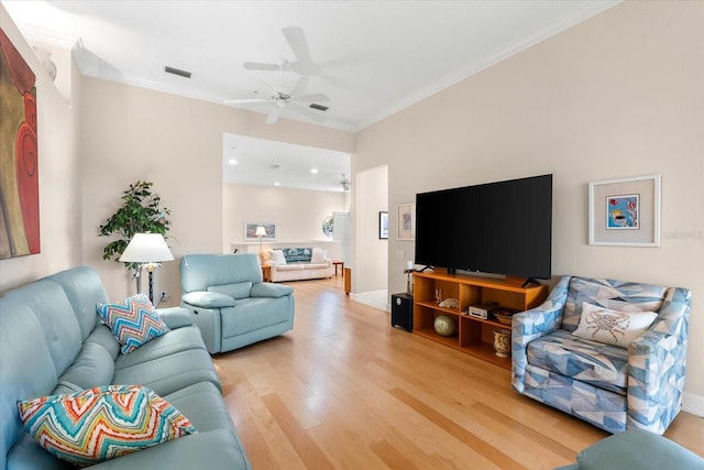 living area featuring visible vents, baseboards, ornamental molding, ceiling fan, and light wood-style flooring