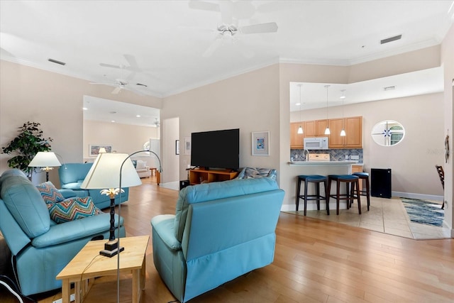 living area with light wood finished floors, ceiling fan, and visible vents