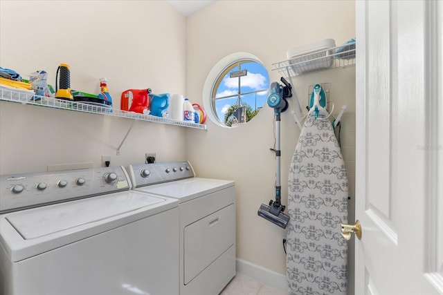 washroom featuring washer and clothes dryer, light tile patterned flooring, laundry area, and baseboards