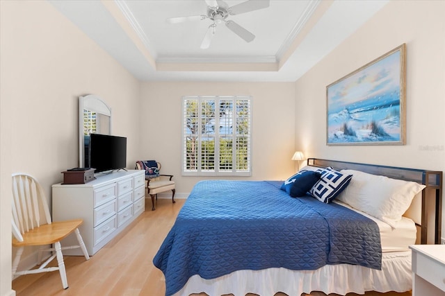 bedroom featuring light wood-type flooring, multiple windows, a tray ceiling, and crown molding
