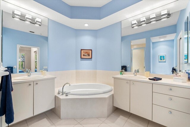 full bathroom featuring a shower stall, two vanities, a garden tub, and a sink