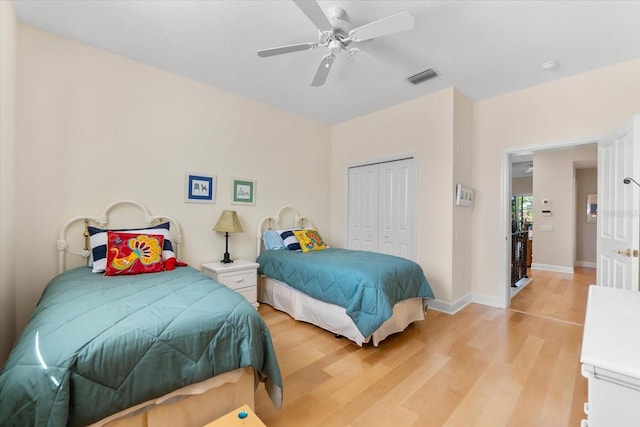 bedroom with baseboards, a closet, light wood-style floors, visible vents, and ceiling fan