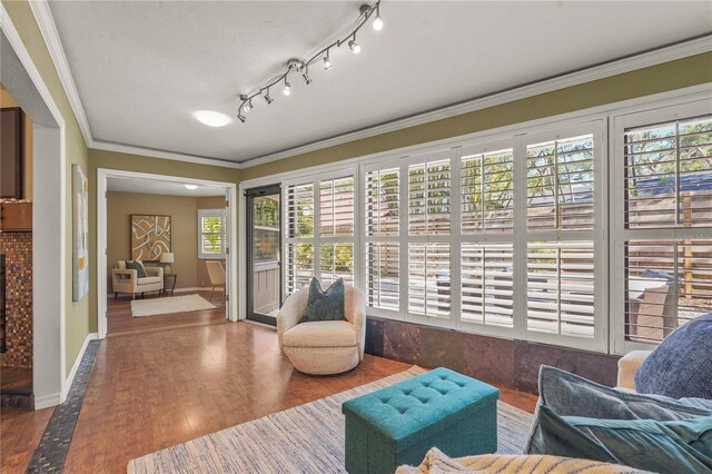 living area featuring crown molding, baseboards, and wood finished floors