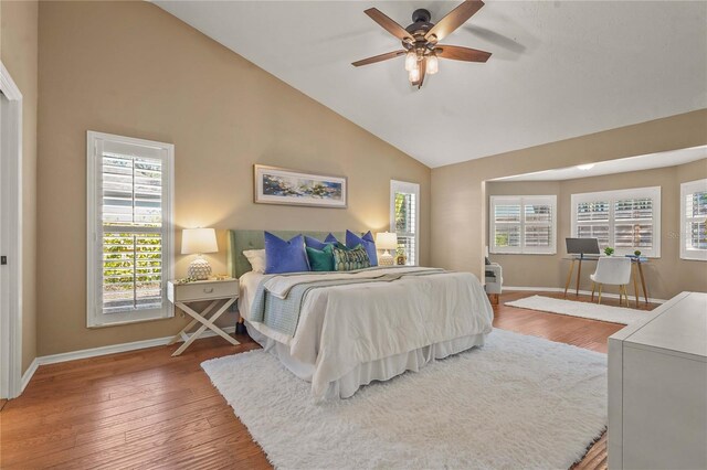 bedroom featuring baseboards, ceiling fan, wood finished floors, and high vaulted ceiling
