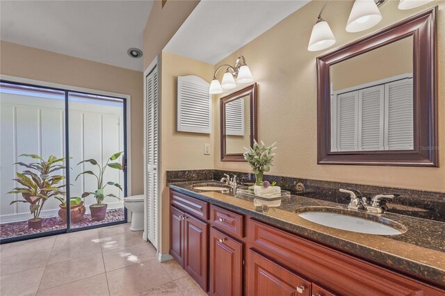 full bath featuring double vanity, toilet, a sink, and tile patterned flooring