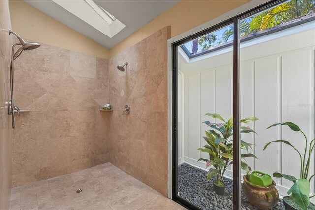 bathroom with a tile shower and lofted ceiling with skylight