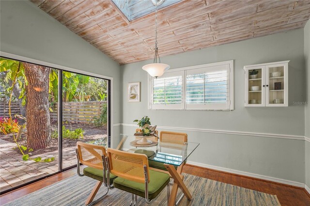 dining area featuring baseboards, wooden ceiling, wood finished floors, and vaulted ceiling with skylight