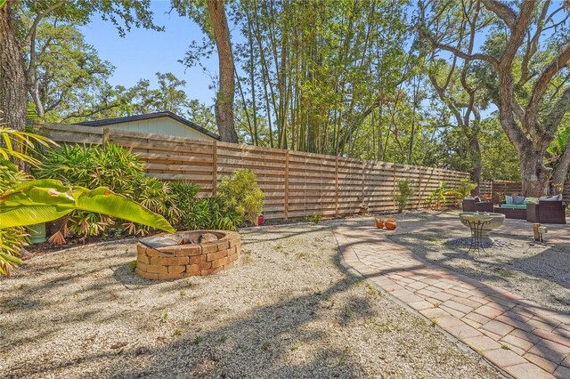 view of yard featuring a patio, a fenced backyard, and an outdoor living space with a fire pit