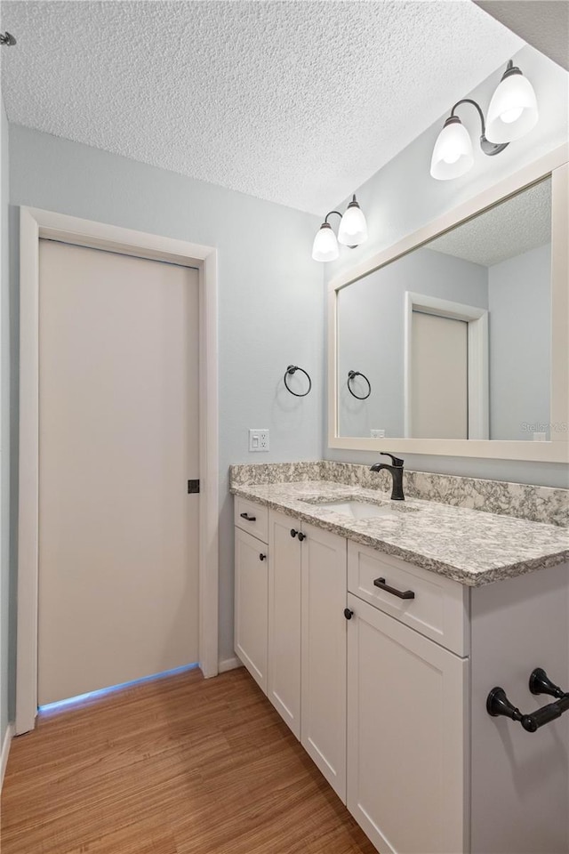 4570 Pinebrook Cir Unit 406, Bradenton, FL 34209 - bathroom featuring a textured ceiling, baseboards, vanity, and wood finished floors