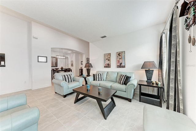 living area featuring arched walkways, light tile patterned floors, visible vents, and baseboards