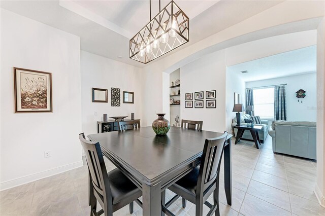 dining area featuring arched walkways, light tile patterned floors, baseboards, and a notable chandelier