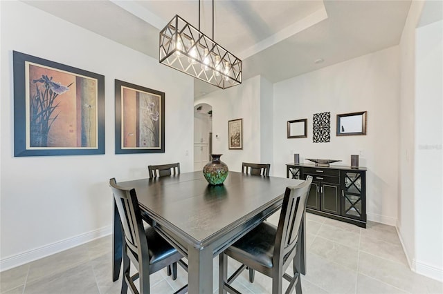 dining area with arched walkways, light tile patterned floors, and baseboards