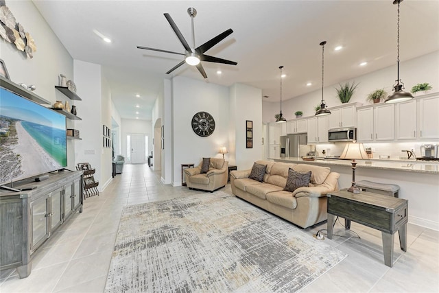 living room featuring light tile patterned floors, ceiling fan, recessed lighting, and a high ceiling