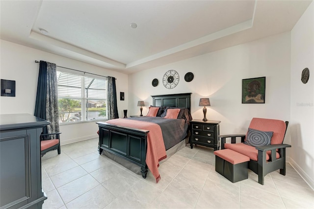 bedroom featuring a tray ceiling and baseboards