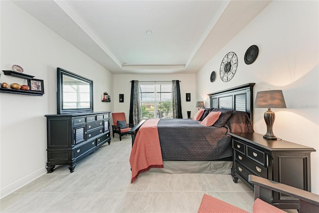 bedroom featuring a tray ceiling, light tile patterned flooring, and baseboards