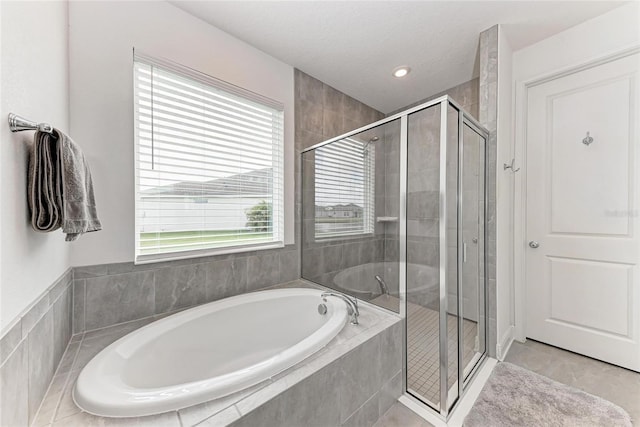 full bath with a shower stall, a textured ceiling, and a garden tub