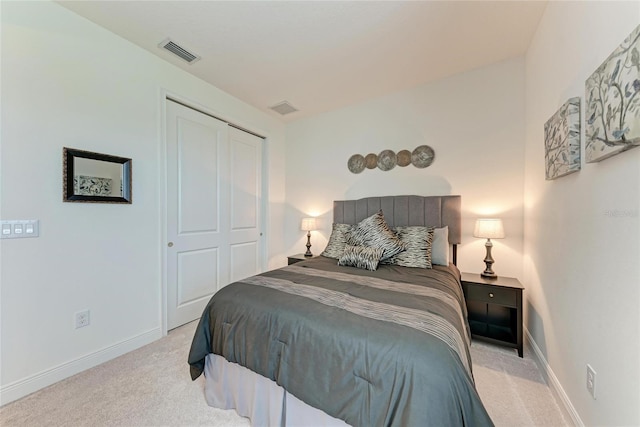 bedroom with a closet, visible vents, light colored carpet, and baseboards