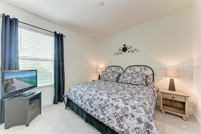 bedroom featuring light carpet and baseboards