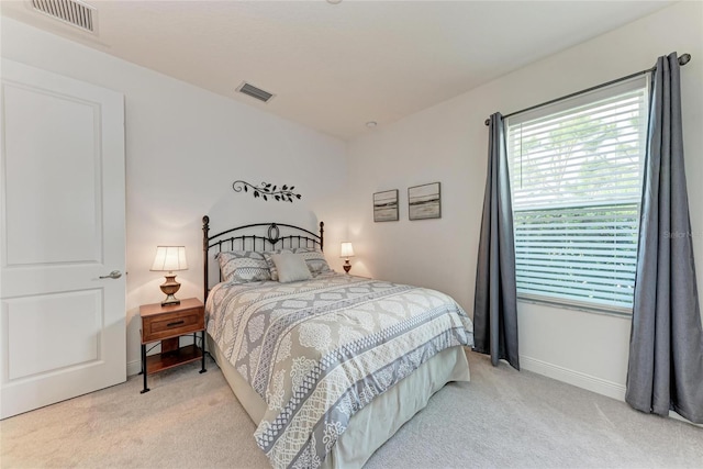 bedroom featuring visible vents, light colored carpet, and baseboards