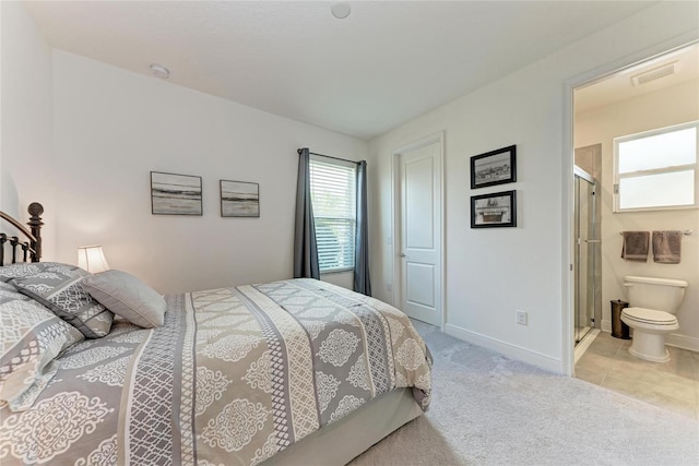 bedroom with light carpet, baseboards, visible vents, and ensuite bath