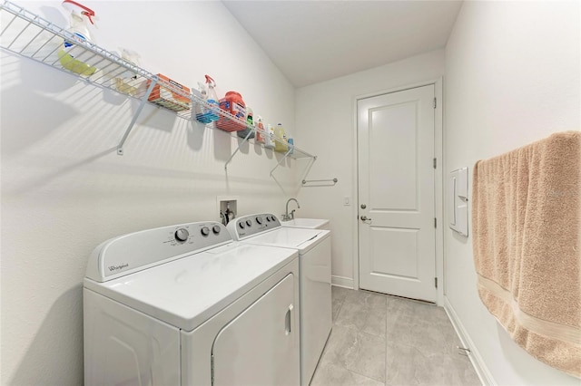 clothes washing area featuring a sink, baseboards, separate washer and dryer, and laundry area