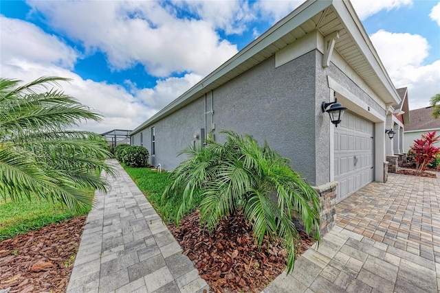 view of side of home featuring driveway, stucco siding, and a garage