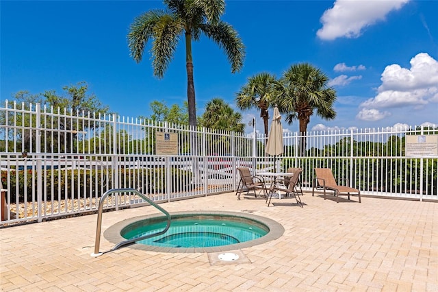 view of swimming pool with fence, a patio, and a community hot tub