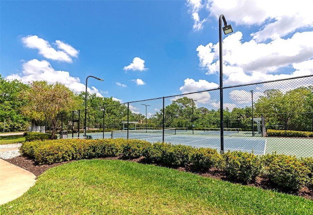 view of sport court featuring fence and a yard