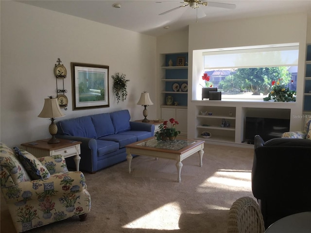 living room with carpet flooring, a ceiling fan, and built in shelves