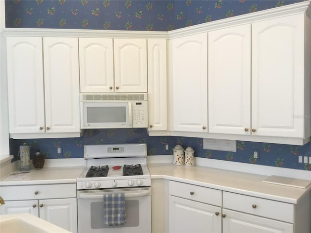 kitchen featuring white cabinets, wallpapered walls, and white appliances