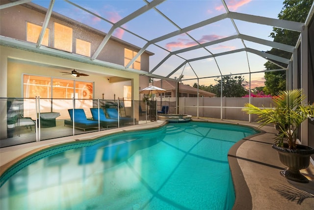pool at dusk with a lanai, a patio, a pool with connected hot tub, and a ceiling fan