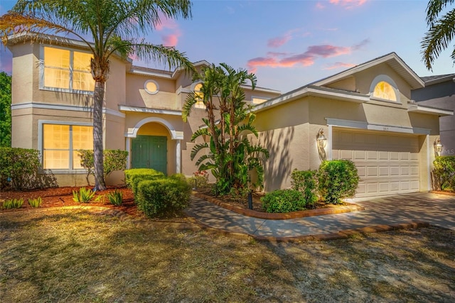 mediterranean / spanish-style home with an attached garage, driveway, and stucco siding