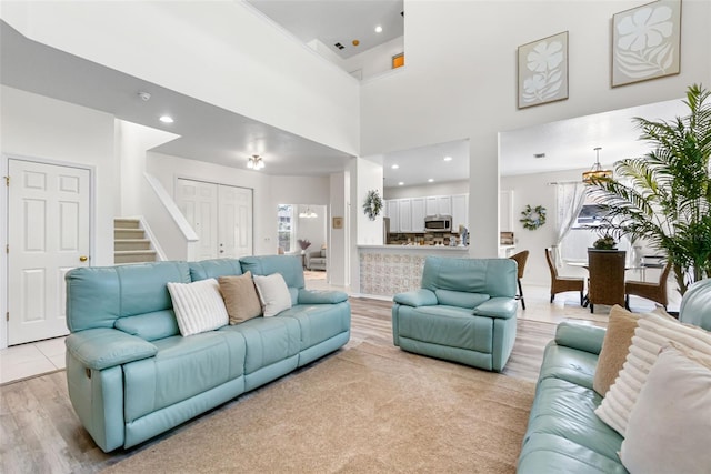 living room featuring stairway, recessed lighting, light wood finished floors, and a towering ceiling