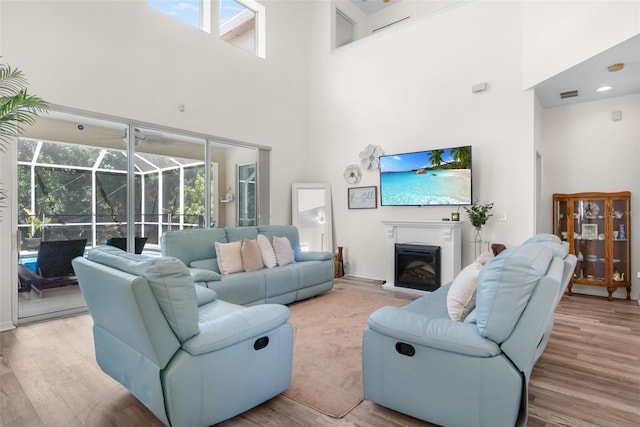 living area featuring visible vents, a high ceiling, a sunroom, and a wealth of natural light