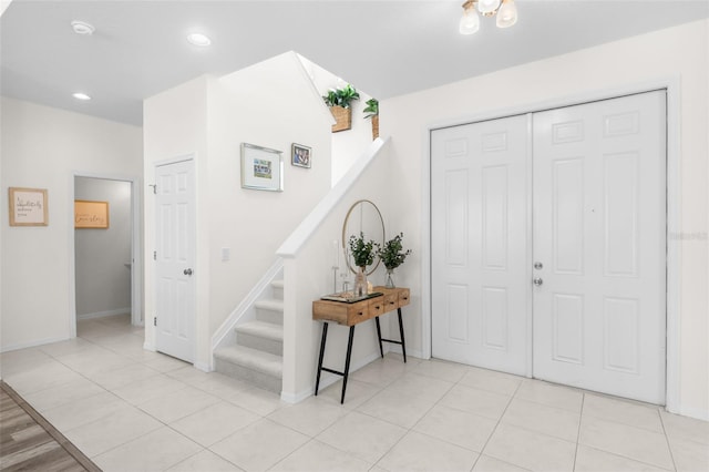 foyer with baseboards, recessed lighting, and stairway