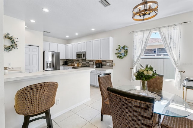 kitchen featuring visible vents, tasteful backsplash, a sink, a chandelier, and stainless steel appliances