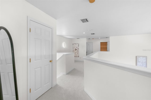 corridor with visible vents, recessed lighting, baseboards, and light colored carpet