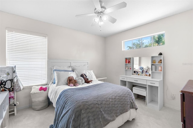 bedroom with light colored carpet, a ceiling fan, and baseboards