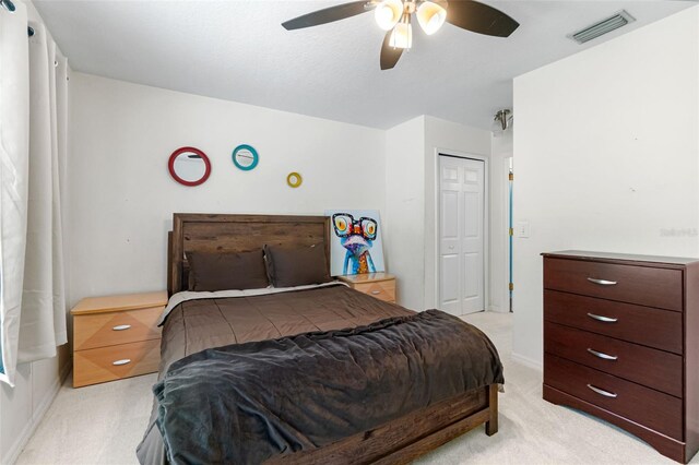 bedroom with light colored carpet, a ceiling fan, baseboards, visible vents, and a closet