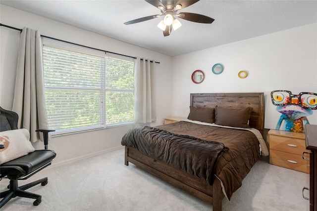 bedroom featuring baseboards, multiple windows, light carpet, and ceiling fan