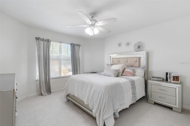 bedroom featuring light colored carpet, a ceiling fan, and baseboards