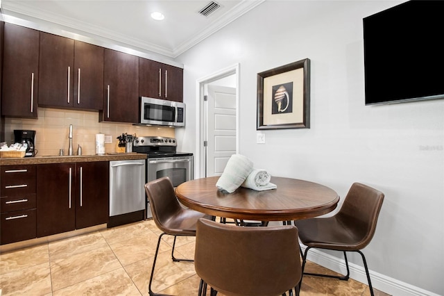 1020 Sun N Sea Dr Unit 104B, Sarasota, FL 34242 - kitchen with appliances with stainless steel finishes, visible vents, dark brown cabinets, ornamental molding, and backsplash
