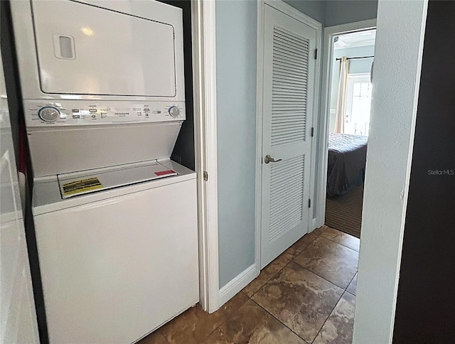 1020 Sun N Sea Dr Unit 104B, Sarasota, FL 34242 - clothes washing area featuring stacked washer / drying machine, dark tile patterned floors, laundry area, and baseboards